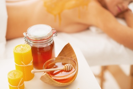 Closeup on honey spa therapy ingredients and relaxed young woman in background